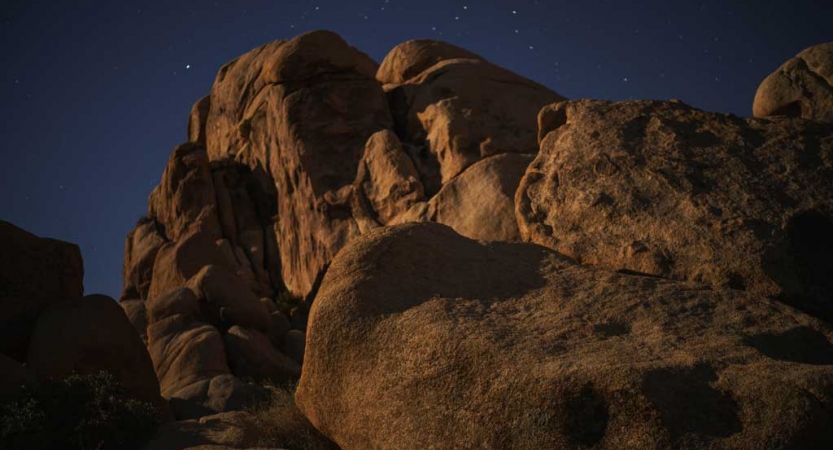 a large rock formation juts upwards towards the night sky, dotted with stars